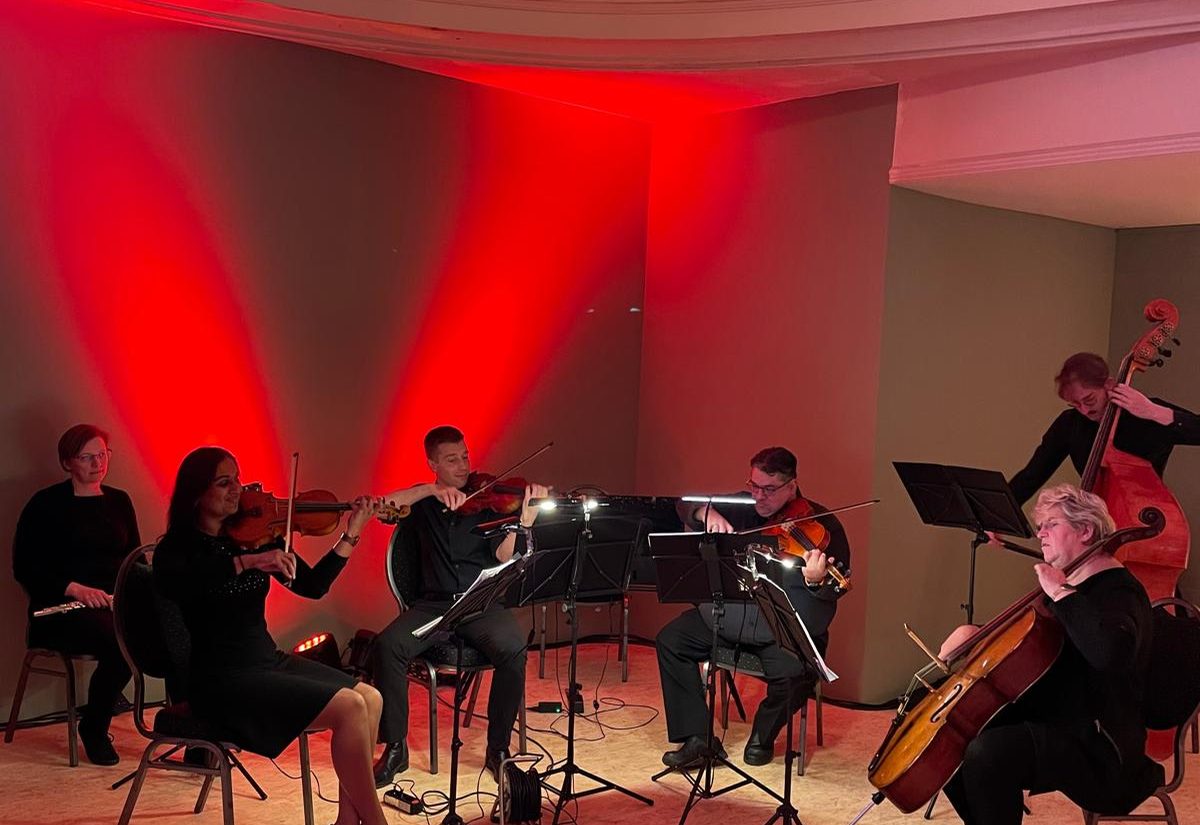 Streichquintett spielt im Festsaal vor rot angestrahlter Wand